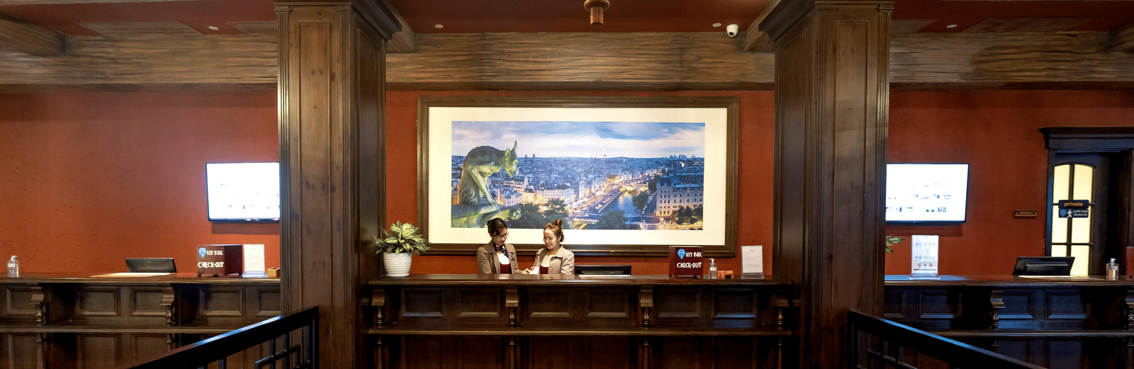 a carpeted front desk lobby with cosy interiors and two staff members standing behind the desk